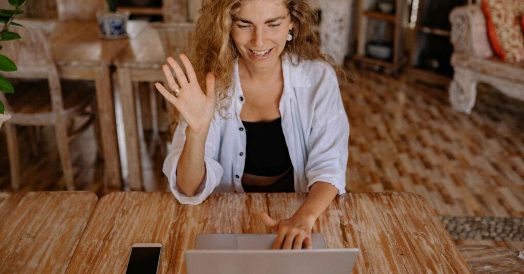 woman waving at laptop